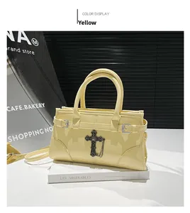 Close-up of bright yellow patent leather handbag with black cross and chain detail