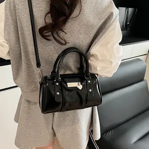 Glossy black Boston pillow bag with silver rivets and heart charm on female model