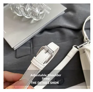 Detail of adjustable white leather strap with silver buckle on minimalist handbag