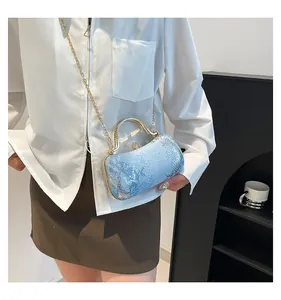 Detail of light blue snake texture evening bag with gold handle and jewel clasp
