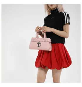 Detail view of the pink patent leather handbag with black metal cross charm and buckles