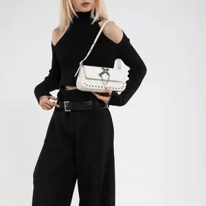 White rivet square crossbody bag with metal cross chain shown on a model in minimalist style