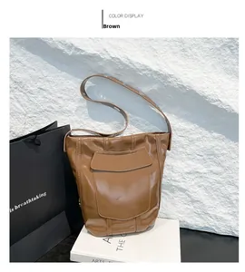 Détail du sac seau marron avec rivets argentés et texture de cuir synthétique brillant