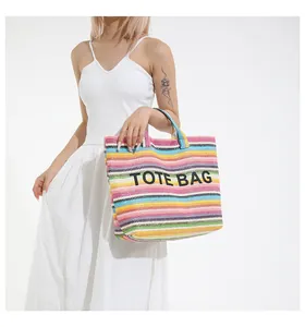 Gros plan du sac cabas en paille rayé multicolore avec broderie texte TOTE BAG noire