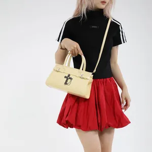 Cream leather tote bag with gothic cross pendant and top handles shown on model