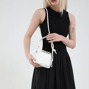 Minimalist white PU leather box bag with silver studs, shown on a model in a studio setting