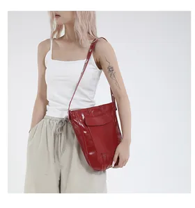 Dettaglio di una borsa a secchiello in pelle lucida rosso scuro con cuciture a vista
