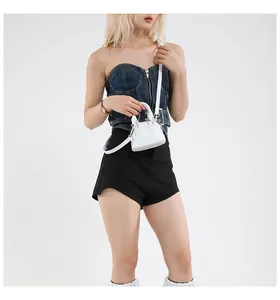 Gros plan d'un mini sac à main blanc avec bandoulière porté par un mannequin élégant