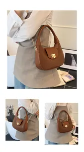 Detail of brown faux crocodile leather crescent bag with gold chain and metal clasp