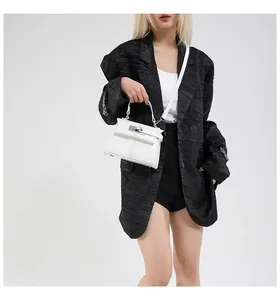 Close-up of white leather handbag featuring metal twist lock and elegant top handle strap