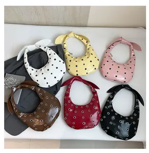 Flat lay of trendy rivet hobo bags in six vibrant colors with stylish bow handles