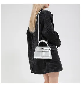 Chic silver mini Kelly style bag with metallic finish shown on a model's outfit