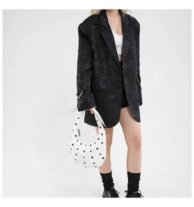 Chic styling of a white eyelet crescent shoulder bag with an oversized black texture blazer