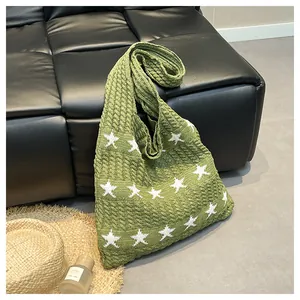 Close-up of green knitted tote bag with white star patterns on a leather sofa