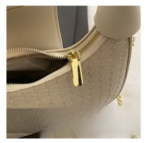 Macro view of golden zipper and hardware details on a woven texture crescent bag
