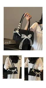 Close-up of black shoulder bag with lace bow detail and wood-grain texture finish