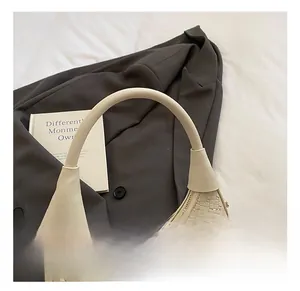 Detail of cream-white woven hobo bag with gold twist lock on a grey suit background