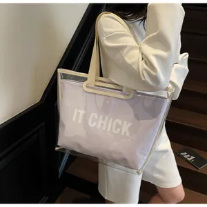 Detail of transparent PVC tote bag with white IT CHICK lettering on the inner purple pouch