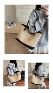 Close-up of large straw tote bag with brown leather trim and metallic brand detail