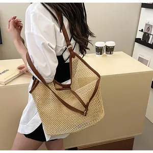 Detail of woven straw mesh tote bag with brown leather handles and large capacity