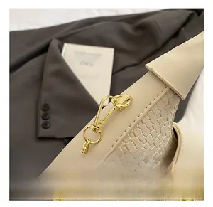 Detailed shot of premium gold hardware hook and woven texture on a beige shoulder bag