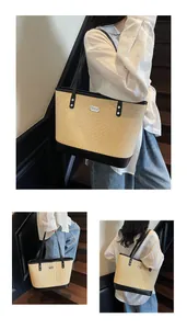 Detail of a large straw tote bag with black contrast trim and metallic brand plaque