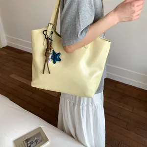 Pale yellow large tote bag with star charm shown on shoulder in minimalist interior