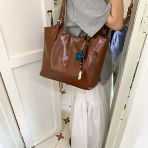Brown oil wax leather tote bag with star and peanut charms on a minimalist shoulder strap