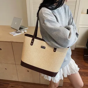 Large woven tote bag with brown leather handles shown in a lifestyle office setting