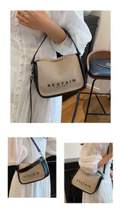 Detail of the canvas and leather拼接 crossbody bag featuring a front lettering design