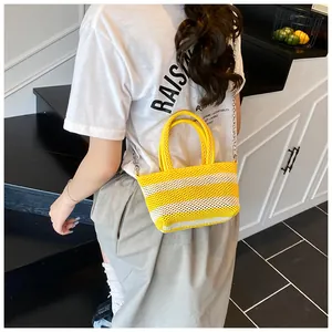Detail of yellow and white striped woven tote with dual handles and silver chain strap