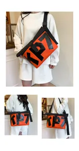 Detail of high-capacity orange and black messenger bag with KP7 print and nylon buckle