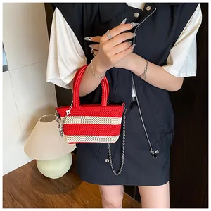 Detail of red and white striped woven tote bag with leather handle and flower charm