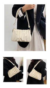 Close-up of pleated cream-white faux leather shoulder bag with gold metal hardware details