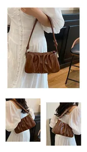 Detail view of deep brown pleated cloud bag with shiny texture and golden hardware