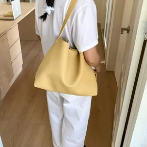 Minimalist bright yellow leather tote bag with lychee texture and matching shoulder strap