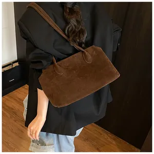 Detail of brown suede tote bag with slim shoulder straps on a black blazer outfit
