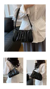 Detail view of the black pleated leather shoulder bag with elegant gold metal buckles
