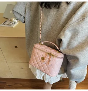 Detail of pink quilted leather vanity bag featuring camellia metal logo and chain strap