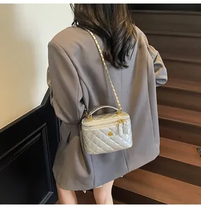 Quilted vanity bag with gold flower logo and chain strap shown on a model