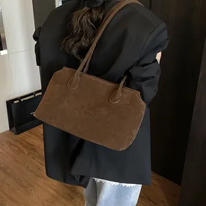 Minimalist brown suede shoulder bag with geometric design worn by model for office