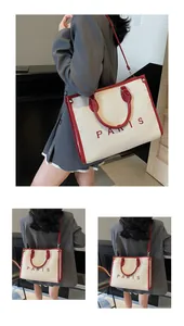 Detalle del bolso tote de lona con ribete de cuero rojo, bordado PARIS y bandolera