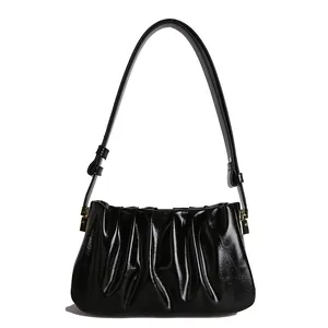 Glossy black pleated cloud shoulder bag with minimalist design and gold hardware