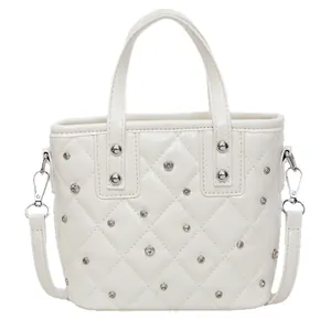White quilted bucket bag with silver studs and top handle on a clean white background