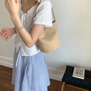 Chic beige woven bucket bag featuring a herringbone texture and a slender shoulder strap