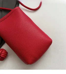Close-up of red litchi texture leather mini phone bag with soft woven buckle detail