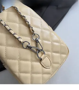 Détail du crochet en métal argenté et de la bandoulière en chaîne sur sac beige