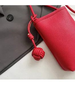 Detailed close-up of a red litchi texture small crossbody phone bag with decorative knot