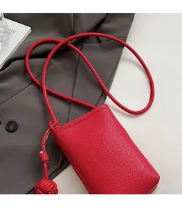Detail of red pebbled leather mini crossbody phone bag with stylish knotted design