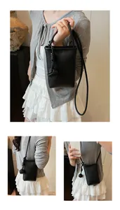Close-up of black lychee grain leather mini bag with elegant knot detail and strap